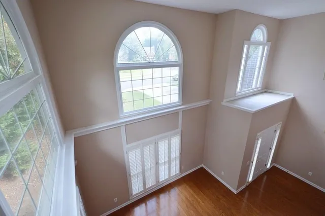 an empty room with wooden floor and windows
