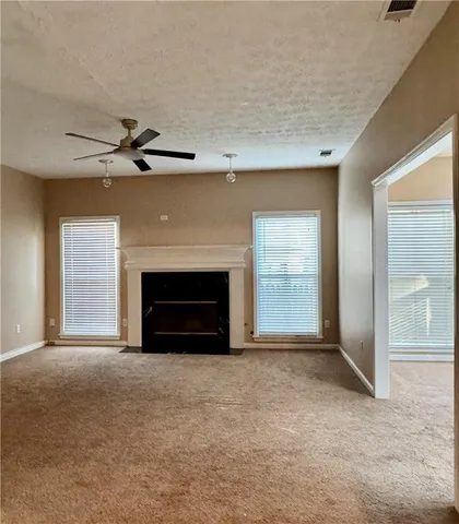 an empty room with windows and fireplace
