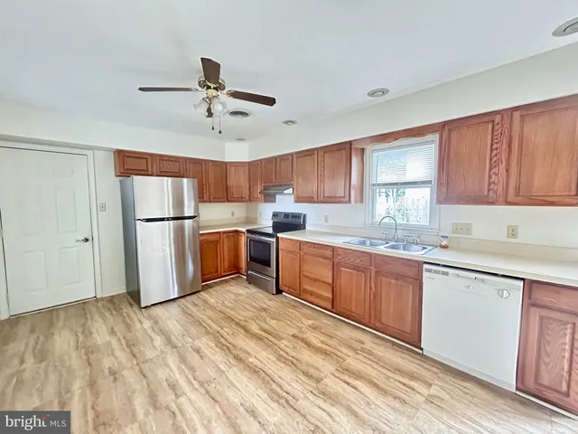a kitchen with granite countertop a refrigerator a sink and white cabinets