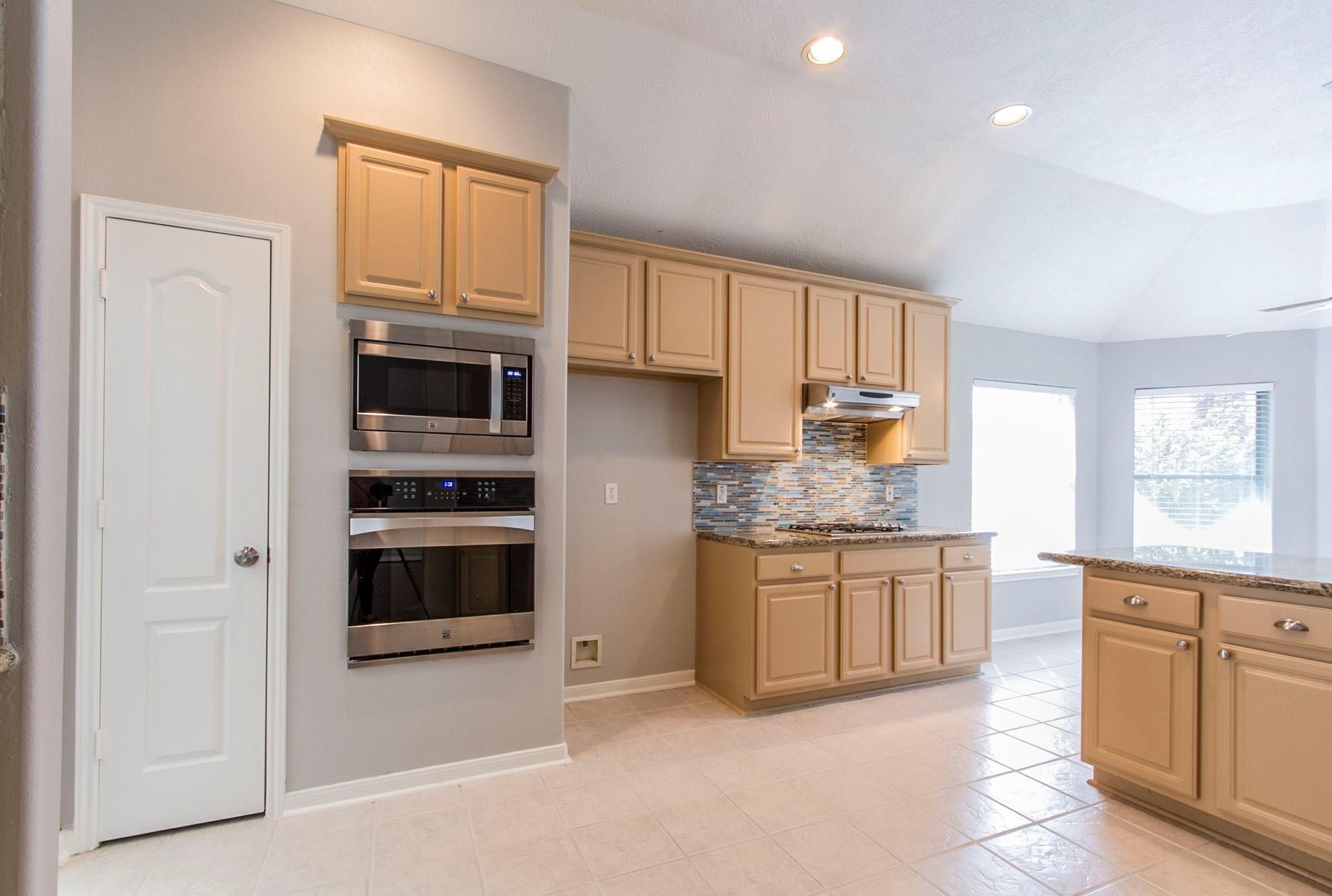 1230 Sienna Hill Drive Houston, TX 77077 - Photo 15 of 42 a kitchen with stainless steel appliances granite countertop a stove a sink and a refrigerator with wooden cabinets