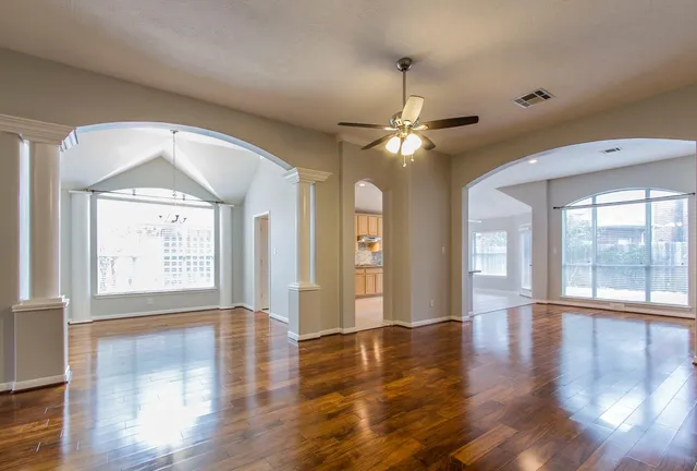 a view of an empty room with wooden floor and a window