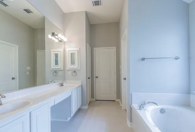 a spacious bathroom with a bathtub sink and mirror