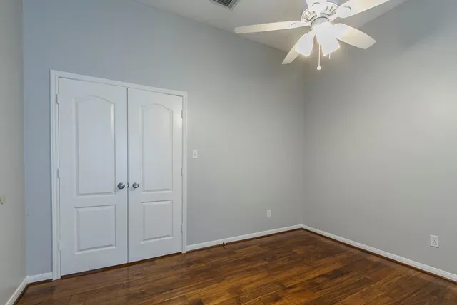 an empty room with wooden floor fan and windows