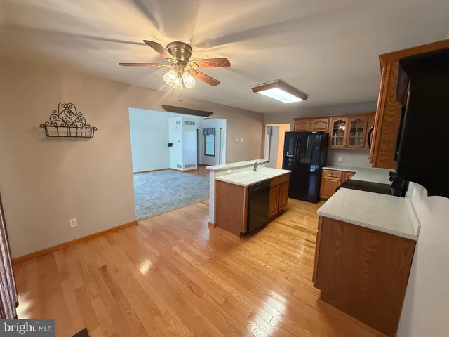 a large kitchen with stainless steel appliances a large counter top a chandelier and a view of living room