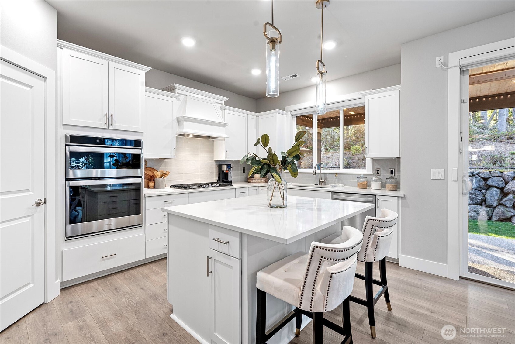 4526 Olympus Loop Gig Harbor, WA 98332 - Photo 10 of 38 a kitchen with stainless steel appliances kitchen island granite countertop a stove a sink a refrigerator and white cabinets with wooden floor