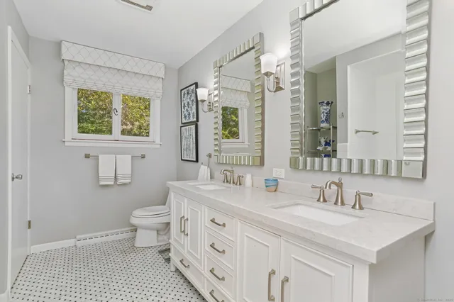 a bathroom with a sink a toilet and a large mirror