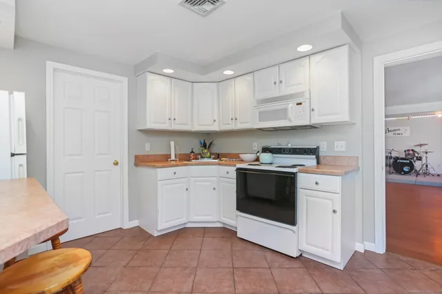 a kitchen with granite countertop white cabinets and white appliances