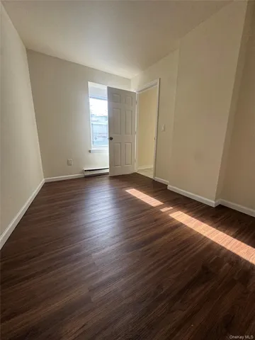 a view of an empty room with wooden floor and window