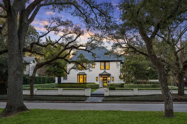 a front view of a house with garden and trees