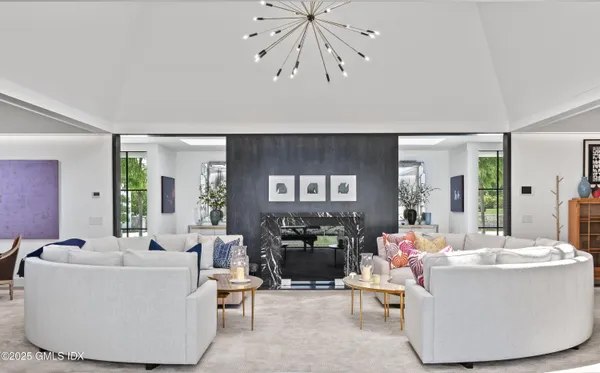 a living room with couches a fireplace and dining table with wooden floor