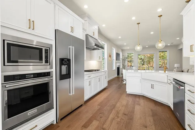 a large kitchen with stainless steel appliances kitchen island granite countertop a stove a sink and a microwave