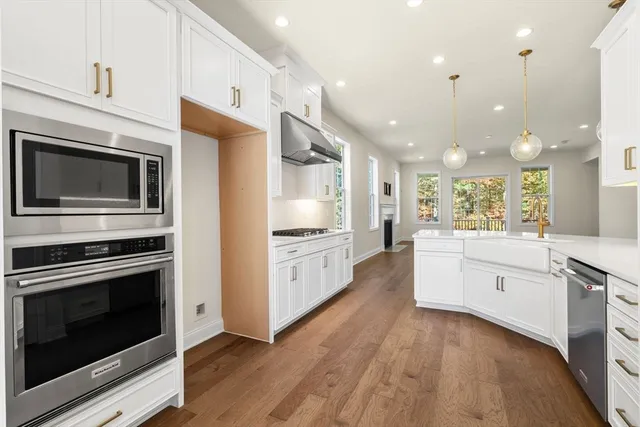 a large kitchen with stainless steel appliances kitchen island granite countertop a stove a sink and a microwave