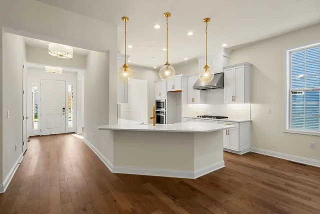 a large kitchen with stainless steel appliances a large counter top a sink a refrigerator and a window