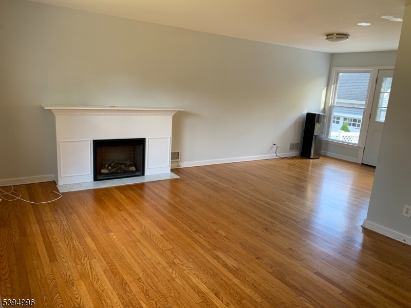 1072 Springfield Avenue New Providence, NJ 07974 - Photo 2 of 20 a view of an empty room with wooden floor fireplace and a window