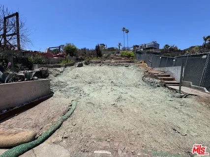 a view of a dry yard with wooden fence