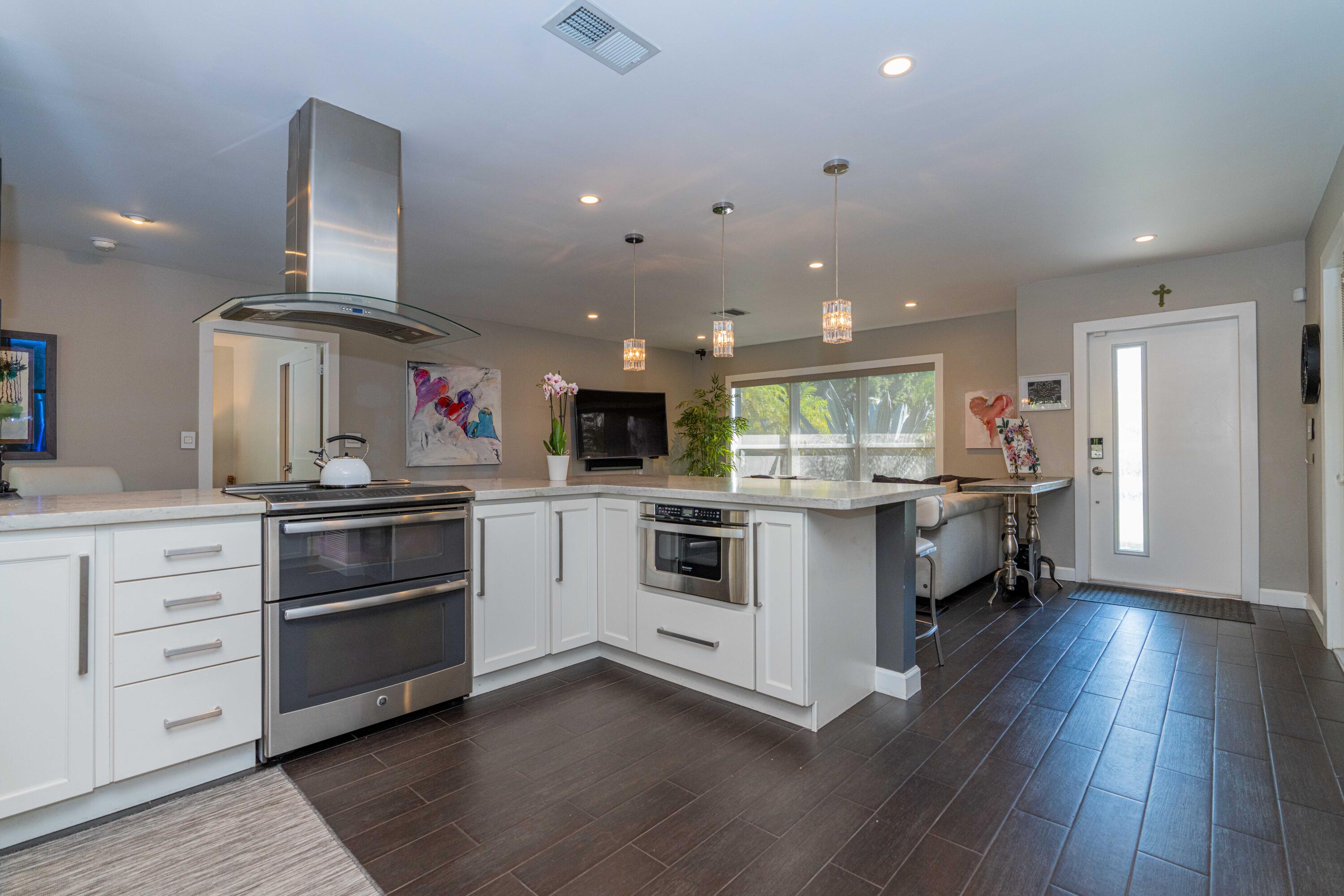 855 Berkley Street Boca Raton, FL 33487 - Photo 10 of 31 a kitchen with stainless steel appliances kitchen island wooden floors and white cabinets
