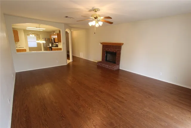 a view of an empty room with window and wooden floor
