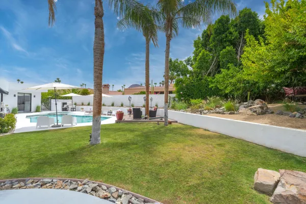 a view of a house with backyard sitting area and swimming pool