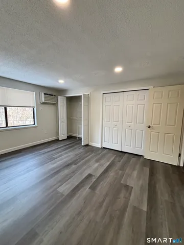 a view of an empty room with wooden floor and window