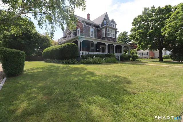 a view of a big house with a big yard and large trees