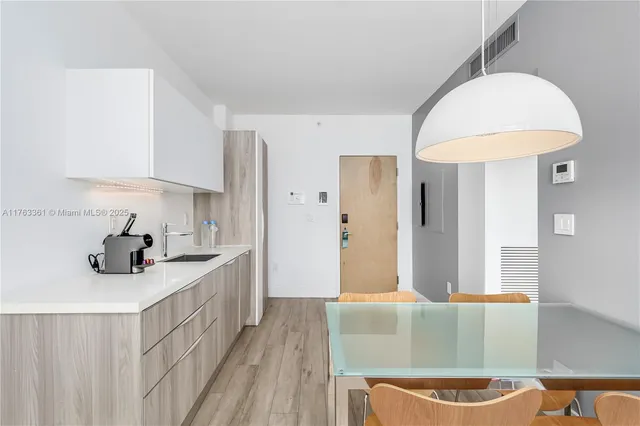 a kitchen with stainless steel appliances a sink a stove a refrigerator cabinets and a dining table