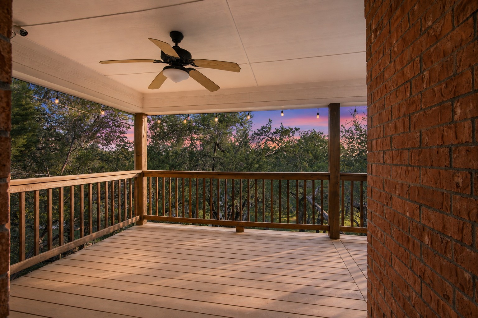 8204 Texas Plume Road Austin, TX 78759 - Photo 36 of 40 A spacious covered patio with a ceiling fan offers serene outdoor living amidst a lush, tree-filled landscape at sunset.