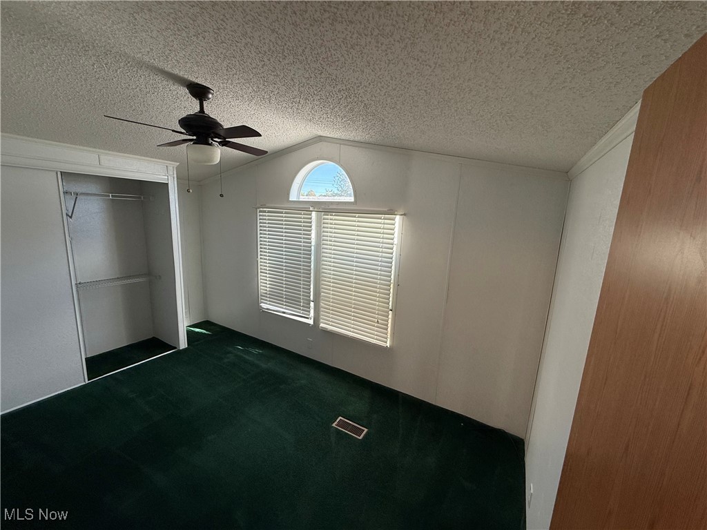 18592 Edwards Road, Unit 137 Doylestown, OH 44230 - Photo 15 of 17 Unfurnished bedroom featuring lofted ceiling, a closet, carpet, a textured ceiling, and a ceiling fan