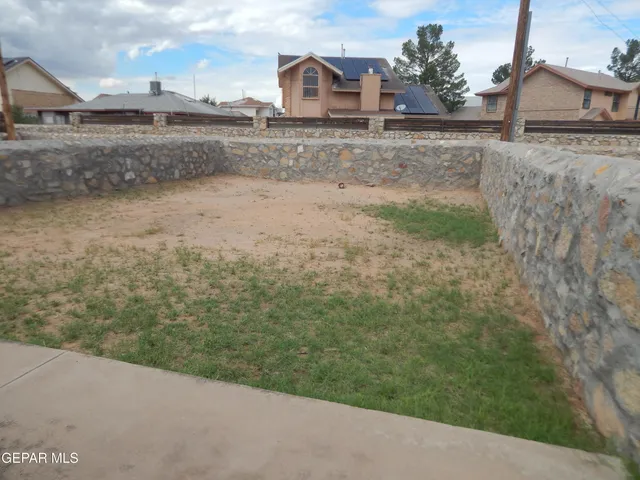 a view of a dry yard with wooden fence