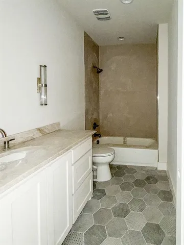 a bathroom with a granite countertop sink a toilet and bathtub