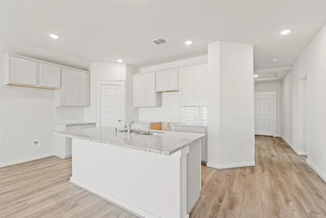 a kitchen with a sink a stove a refrigerator and white cabinets with wooden floor