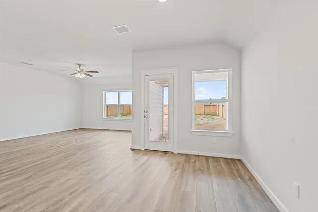 an empty room with wooden floor and windows