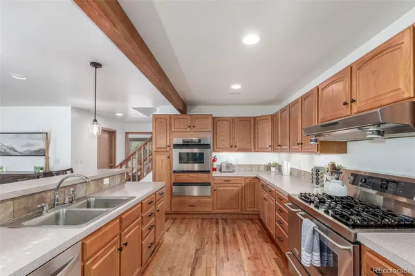a kitchen with kitchen island granite countertop a sink a counter space appliances and cabinets