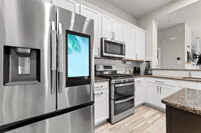 a kitchen with stainless steel appliances granite countertop a refrigerator a stove top oven a sink and dishwasher