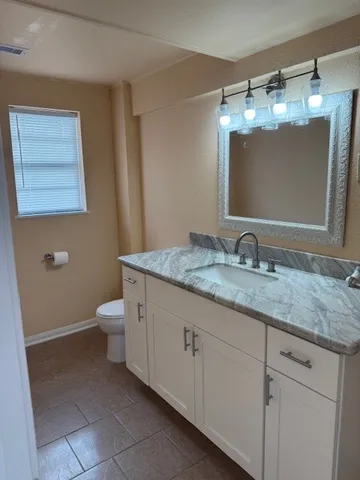 a bathroom with a granite countertop sink a toilet and a mirror
