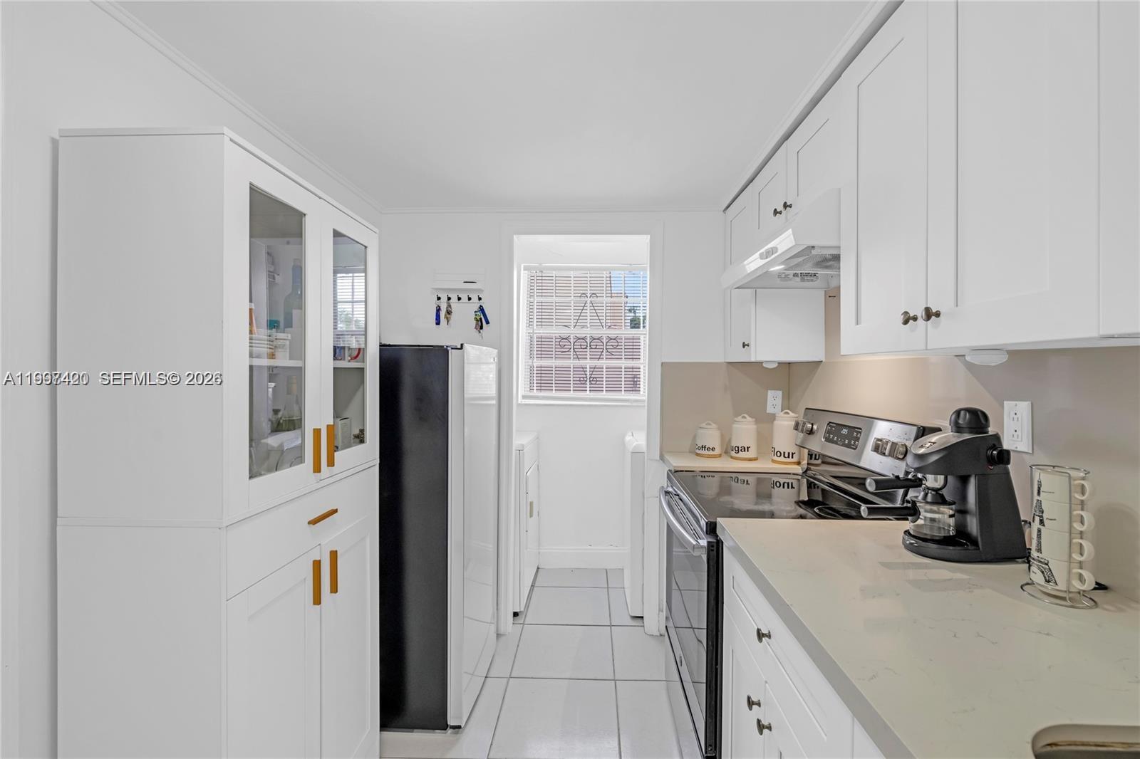 1675 West 57th Street, Unit 514 Hialeah, FL 33012 - Photo 15 of 26 a kitchen with a refrigerator and white cabinets