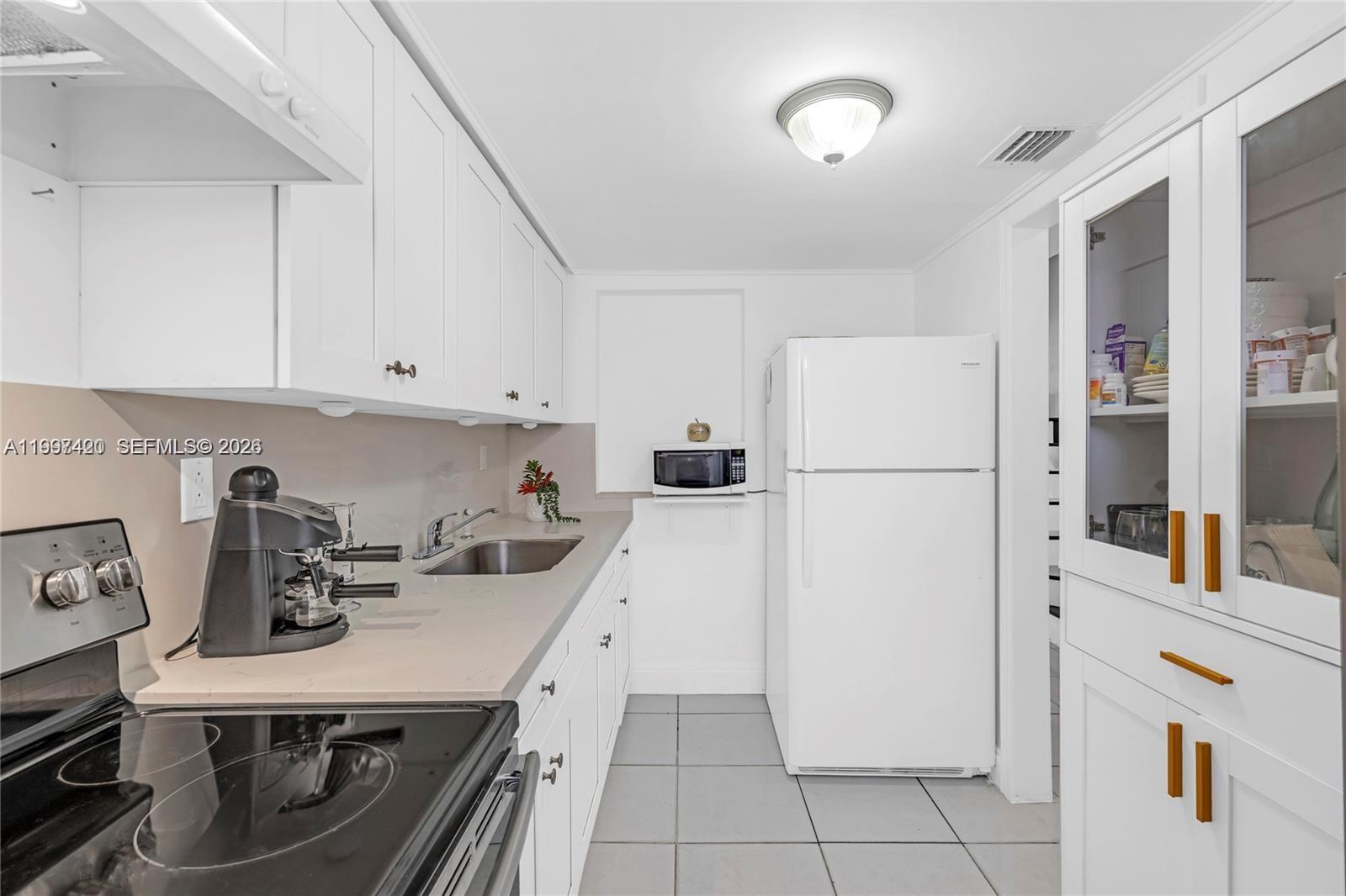 1675 West 57th Street, Unit 514 Hialeah, FL 33012 - Photo 4 of 26 a kitchen with a refrigerator a stove top oven and cabinets