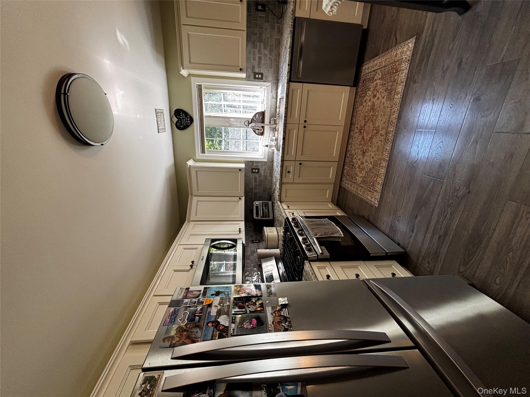 62 Triangle Of Clearwater Road Highland, NY 12528 - Photo 23 of 46 Kitchen with stainless steel appliances, light stone counters, cream cabinetry, dark wood-style floors, and decorative backsplash