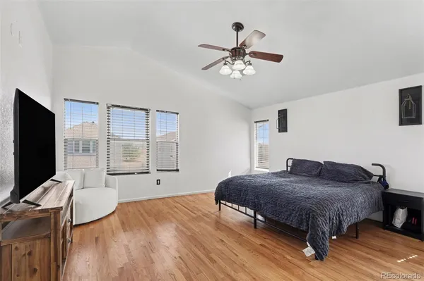 a spacious bedroom with a bed and wooden floor
