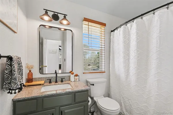 a bathroom with a granite countertop sink mirror vanity and toilet
