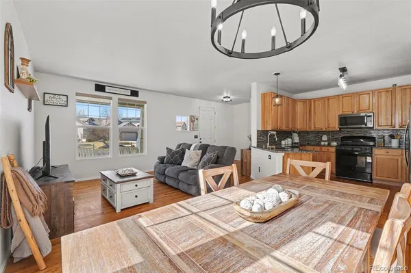 a large kitchen with stainless steel appliances a stove a refrigerator a sink a dining table and chairs with the wooden floor