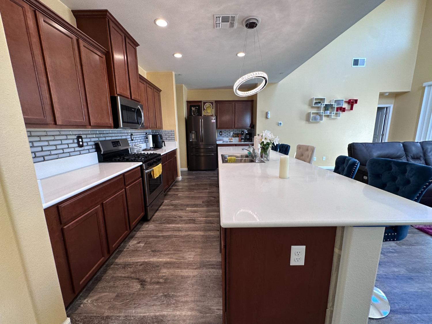 1263 Padre Street Madera, CA 93638 - Photo 6 of 26 a large kitchen with stainless steel appliances a sink a stove a refrigerator a microwave oven with a dining table and chairs