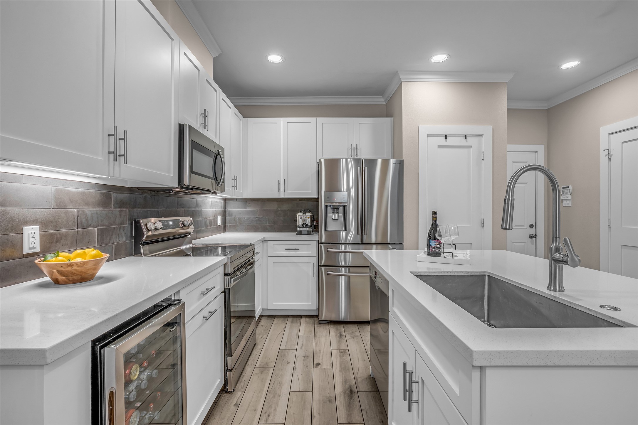 7485 Brompton Street, Unit 7485 Houston, TX 77025 - Photo 4 of 43 Stylish gray backsplash and wood-look tile flooring enhance the contemporary feel, while ample lighting creates a bright and inviting space.