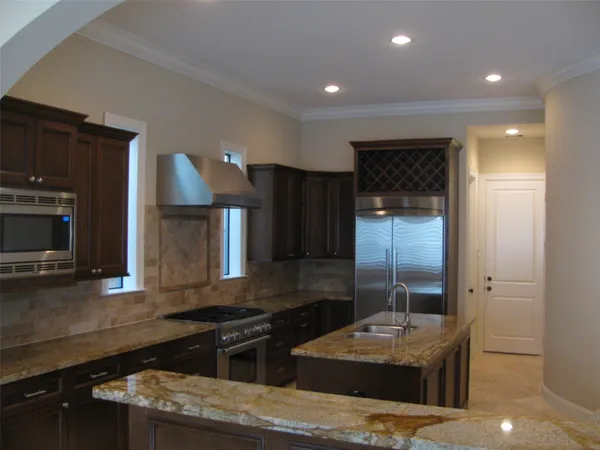 a kitchen with stainless steel appliances granite countertop a sink a stove and a refrigerator