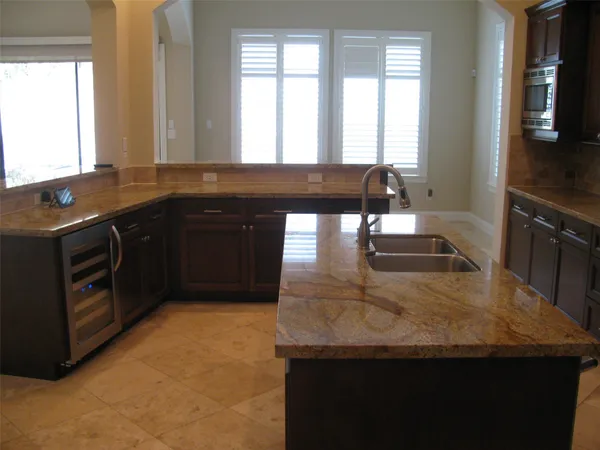 a kitchen with granite countertop a sink a stove and a wooden cabinets