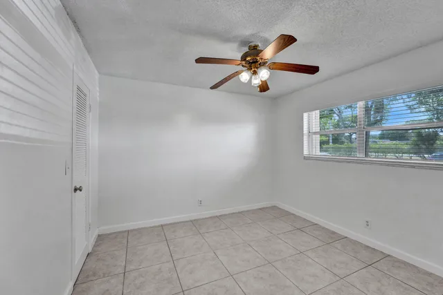 an empty room with windows and fan