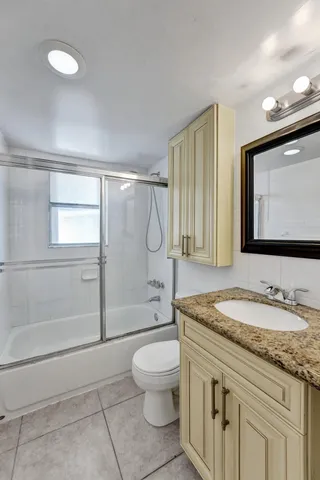 a bathroom with a granite countertop sink a toilet and shower