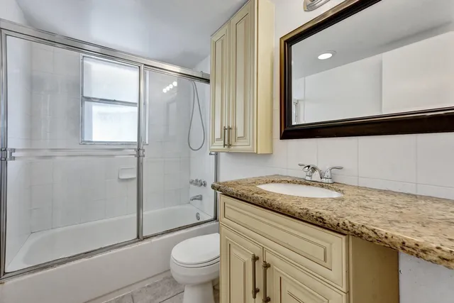 a bathroom with a granite countertop sink toilet and shower