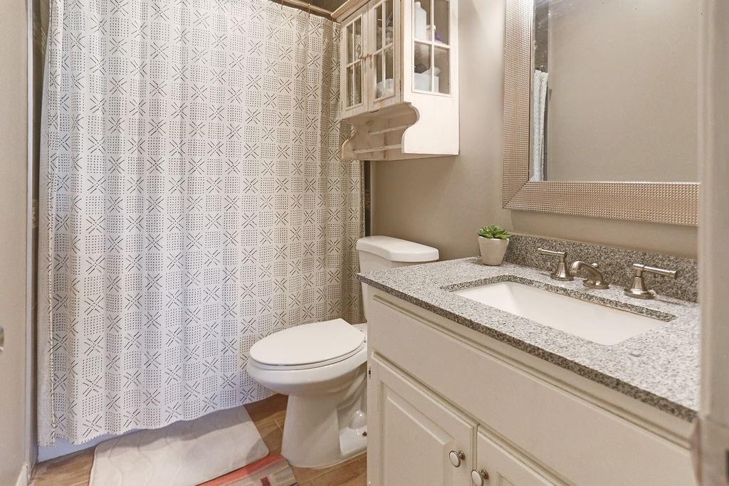 1307 Kinney Avenue, Unit 121 Austin, TX 78704 - Photo 7 of 12 a bathroom with a granite countertop toilet sink and mirror