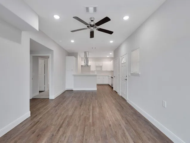 a view of empty room with wooden floor and ceiling fan