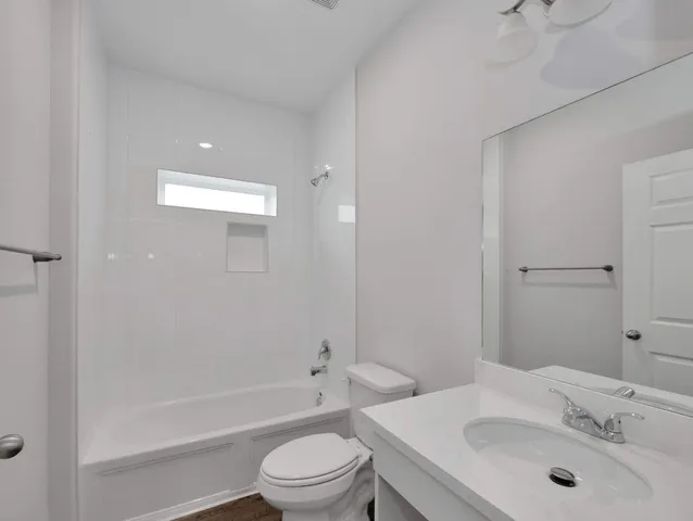 a bathroom with a bathtub shower sink mirror vanity and a toilet
